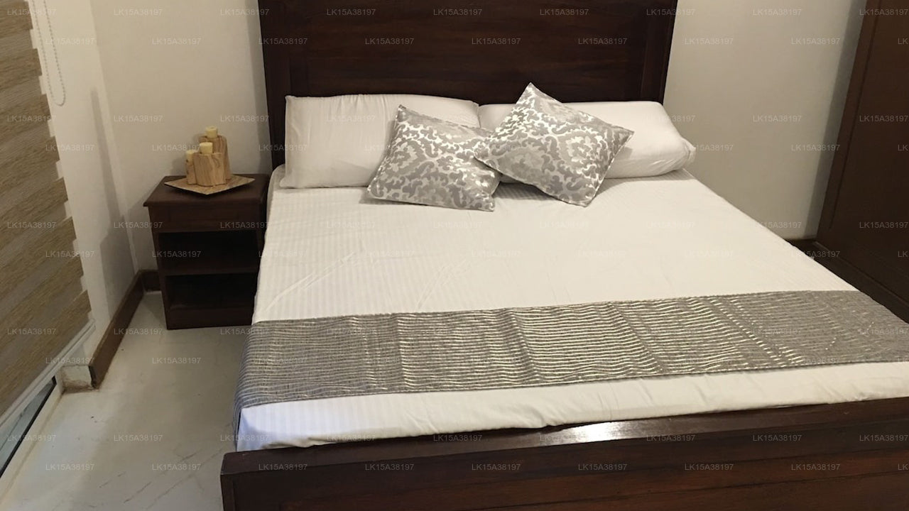 Bedroom with a bed featuring white bedding and decorative pillows, next to a nightstand.