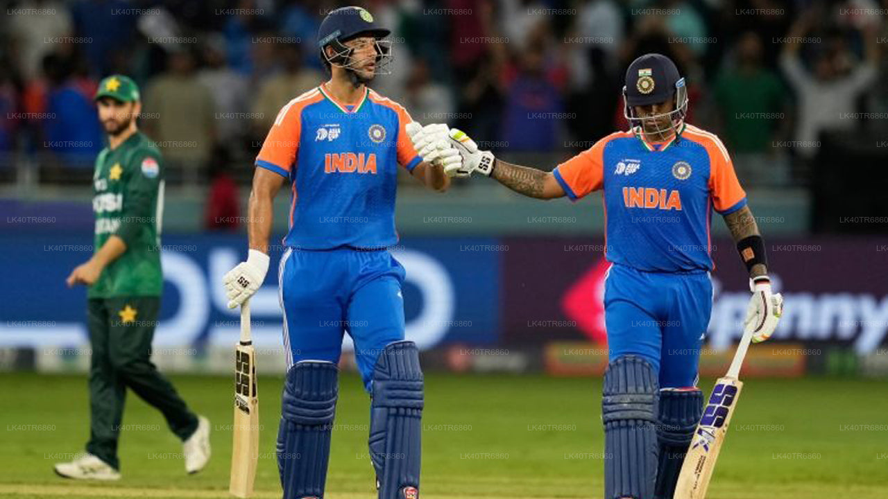Two cricket players from India shaking hands on a cricket field with a player from Pakistan in the background.