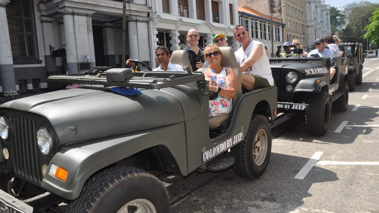 Vintage military-style jeep with people inside on a city street.