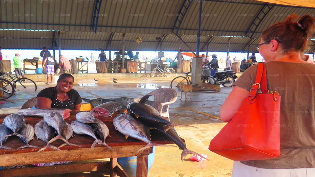 Tourist visiting a Sri Lankan fish market stall with fresh seafood displayed and smiling local vendor.