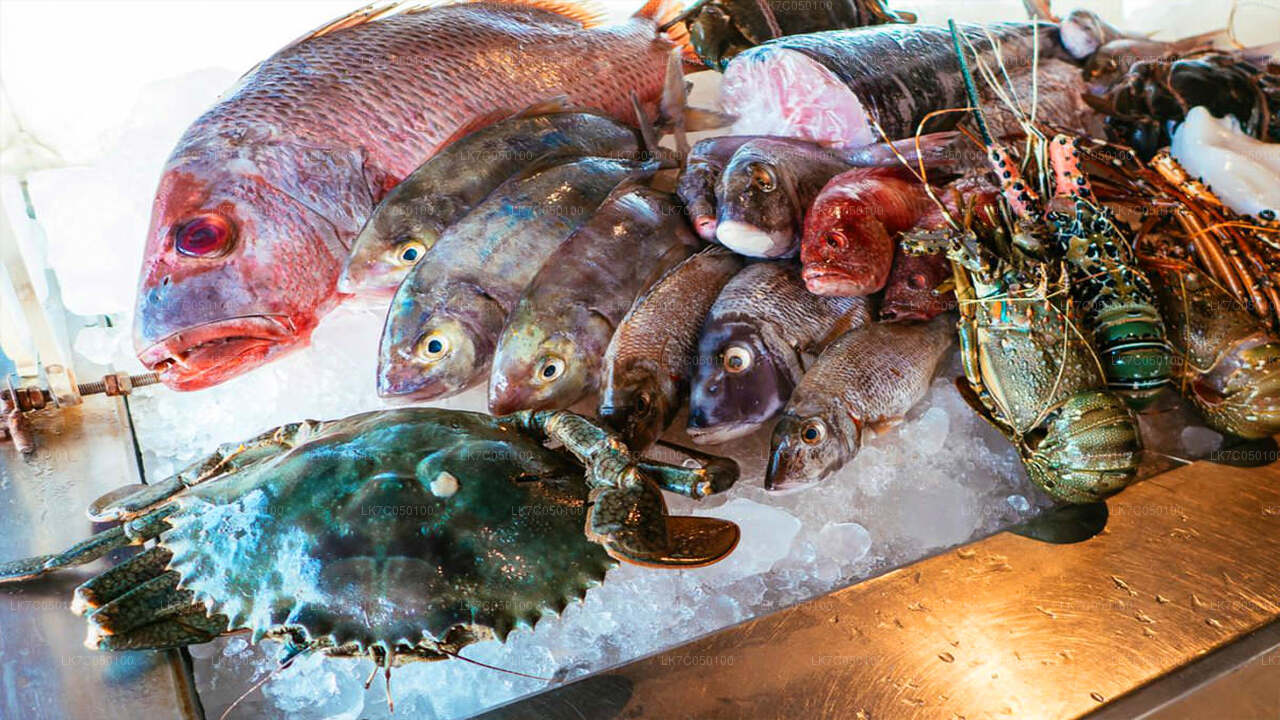Fresh seafood assortment with fish, crab, and lobsters displayed on ice at a Sri Lankan market.